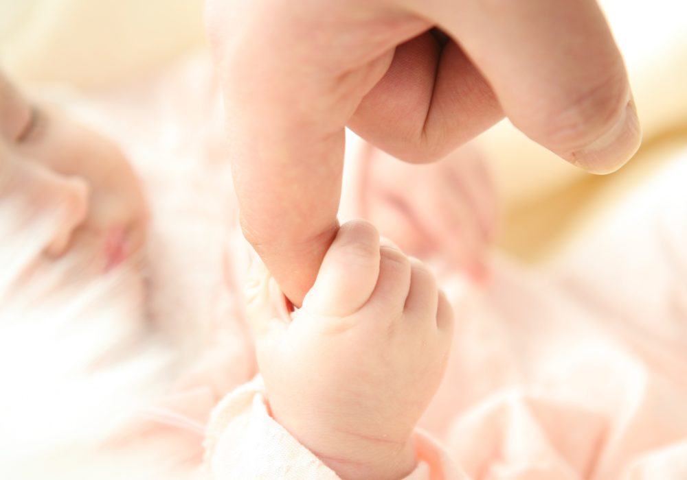 Een waardig en compleet leven in eenheid: baby grijpt vinger van pappa