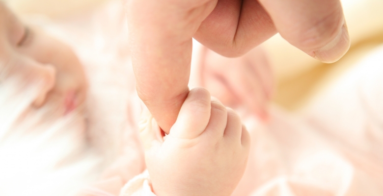 Een waardig en compleet leven in eenheid: baby grijpt vinger van pappa